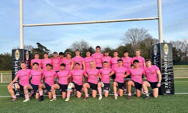 lambs rugby team lined up in 2 rows under rugby posts